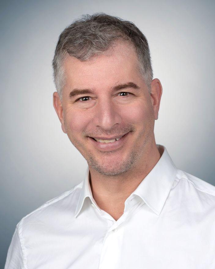 Eric Rainer, Heilpraktiker und Osteopath, lächelnd im weißen Hemd.